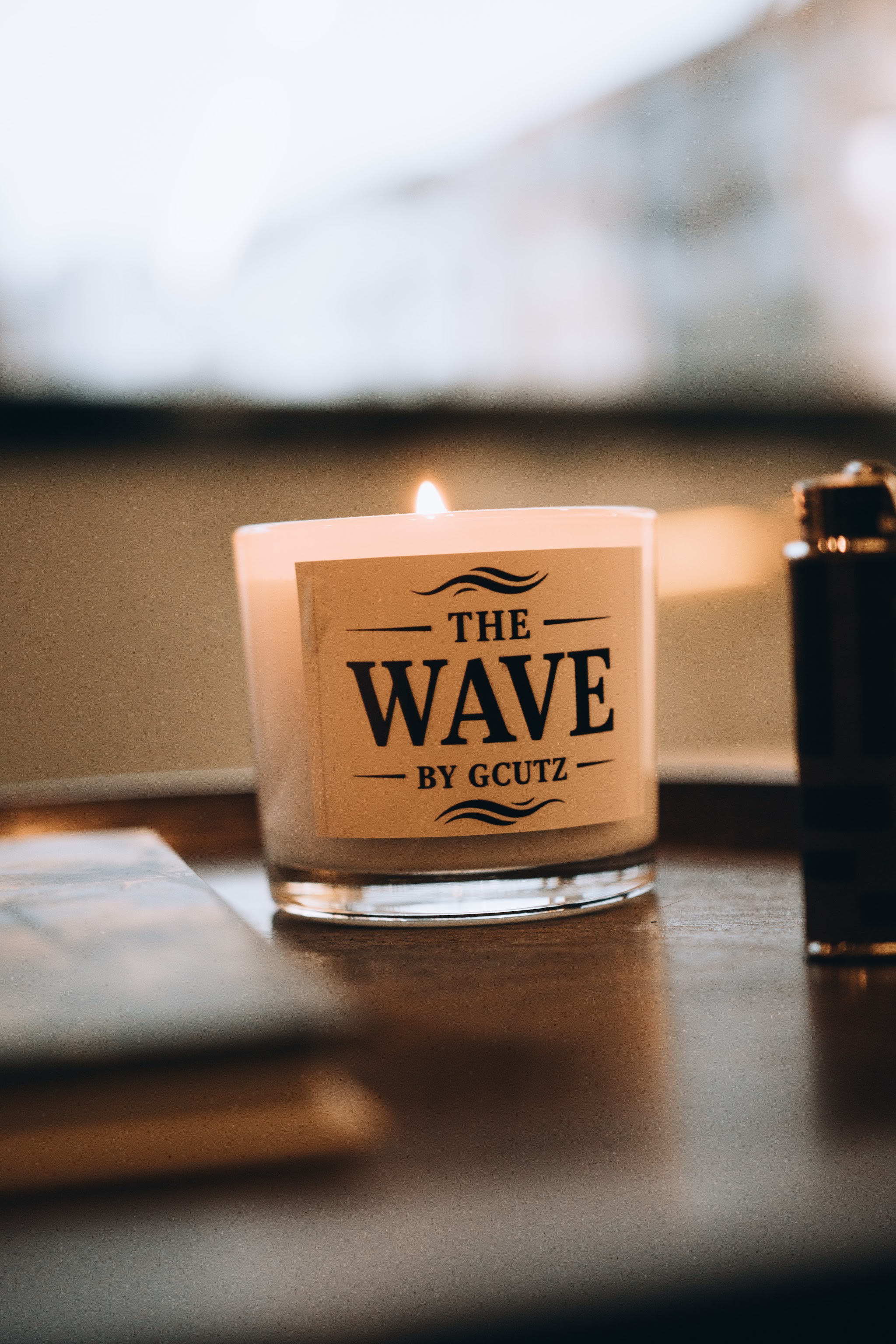 Een brandende kaars met het etiket The Wave by Gcutz